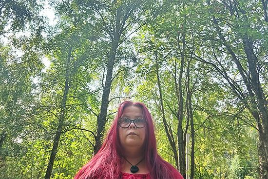 Riikka Miettisen puolipotretti metsässä. 