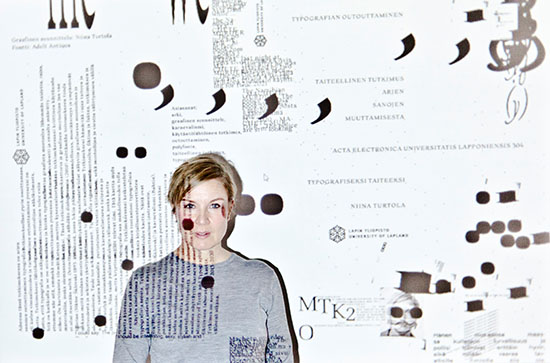 Kuvassa Niina Turtolan puolipotretti ja ympärillä oleviin seiniin heijastettuna sanoja ja merkkejä, eli taiteilija typografisen taiteen keskellä