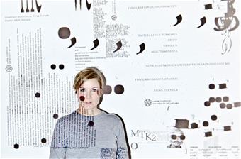 Kuvassa Niina Turtolan puolipotretti ja ympärillä oleviin seiniin heijastettuna sanoja ja merkkejä, eli taiteilija typografisen taiteen keskellä