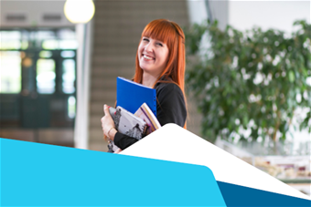 Nuori nainen pitää sylissään kirjoja ja hymyilee.