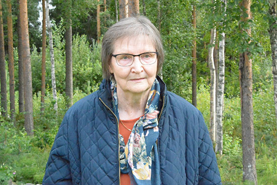 Peterin puolipotretti, jossa hän seisoo metsässä. 