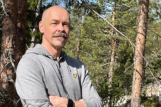 Jukka Kiviniemi, taustallaan kesäistä metsää. Kuva: Markku Ollikainen.