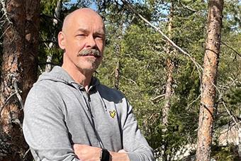 Jukka Kiviniemi, taustallaan kesäistä metsää. Kuva: Markku Ollikainen.