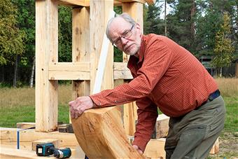 Timo Jokela pitää käsissään kaarevaa hirsiveistoksen osaa. Kuva: Aki Lintumäki.