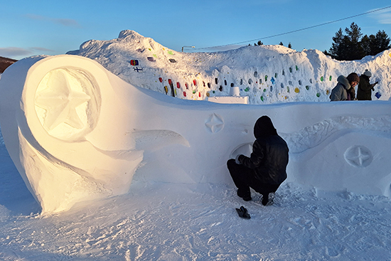 Iso ja kaareva lumiveistos, jossa tähdenmuotoisia yksityiskohtia.
