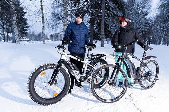 Heikki Huilaja ja Kaisa Lammi seisovat polkupyöriensä kanssa talvisessa maisemassa.