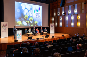 Konferenssin esiintymislava, jossa kuusi panelistia istumassa ja moderaattori seisomassa. Taustalla teksti Rovaniemi Arctic Spirit