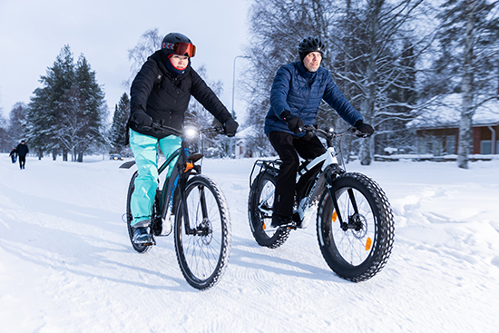 Heikki Huilaja ja Kaisa Lammi pyöräilevät talvisella tiellä.