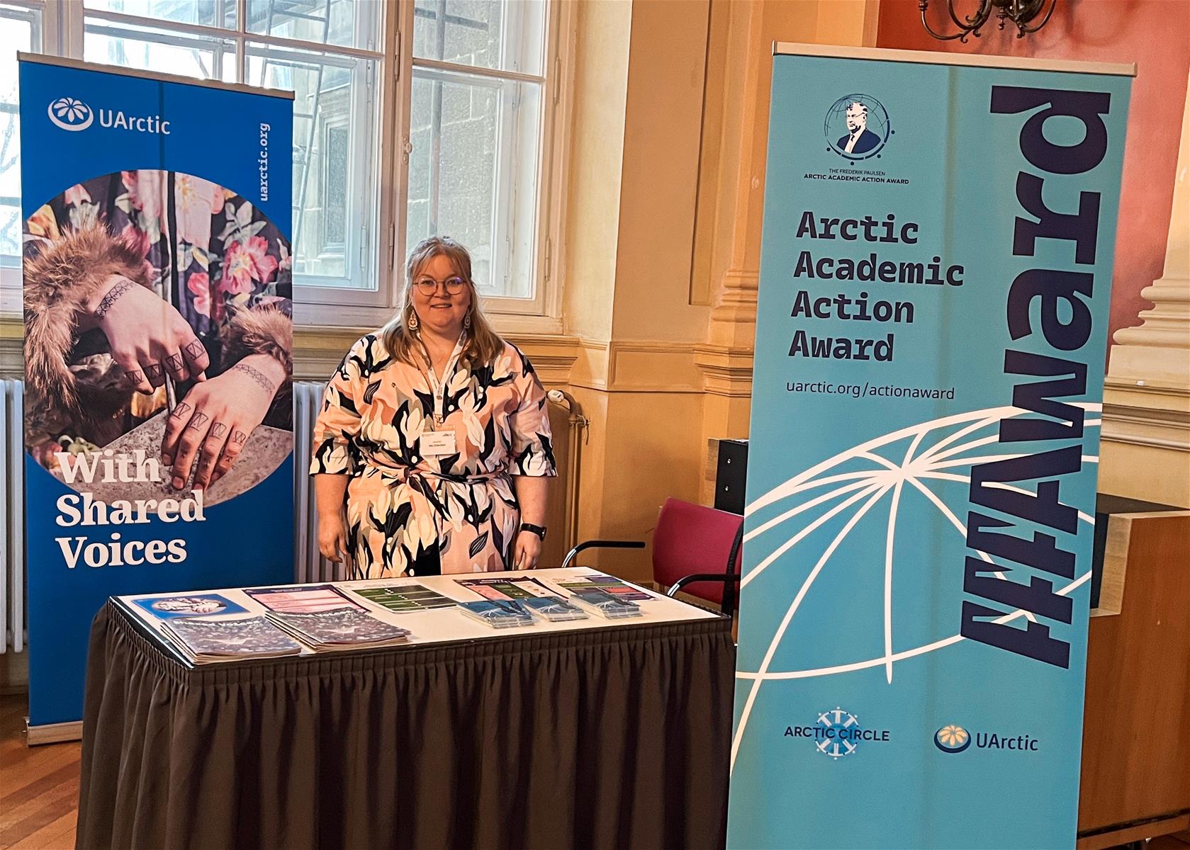 Vaalea nainen mekossa messupöydän takana.