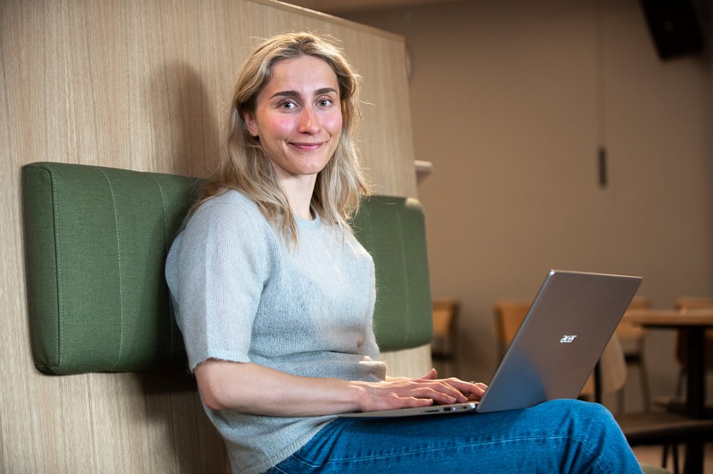 "Nainen istuu penkillä läppäri edessään."