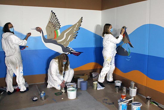 Kuvassa opiskelijat maalaavat autohallissa eläinhahmoja seinään.