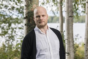 Puolipotretti Lauri Lantelasta, joka nojaa puunrunkoon. 