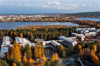 Lapin yliopiston päärakennus ilmasta kuvattuna, taustallaan syksyinen Rovaniemen kaupungin siluetti. Kuva: Ville Rinne.