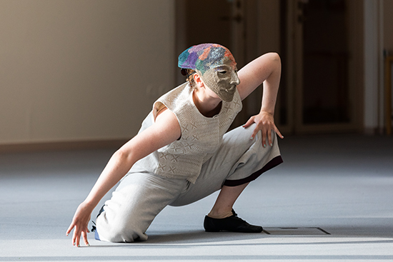 Anniina Ukkonen esiintymässä Tornionlaaksolainen-naamiotanssissa kyyristyneenä. Kasvoillaan hänellä on Johanna Oksasen tekemä, pellavasta virkattu naamio. Kuva: Marko Junttila.