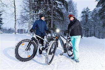 Heikki Huilaja ja Kaisa Lammi seisovat polkupyöriensä kanssa talvisessa maisemassa.