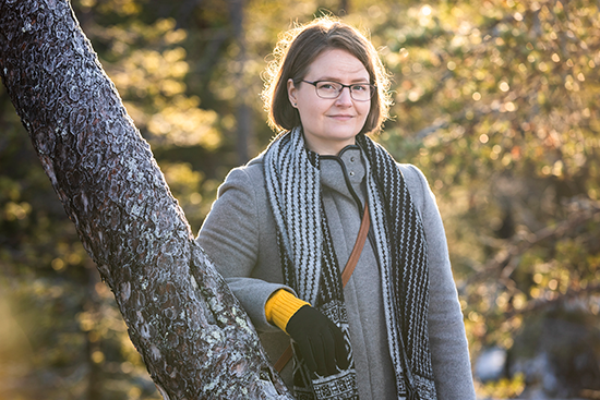 Kuvan puolipotretissa Tiina Harjumaa nojaa puunrunkoon kauniissa syyssäässä. 