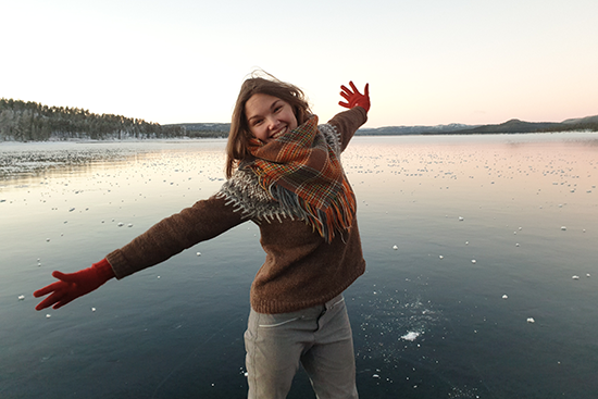 Hymyilevä tanssitaitelija järven jäällä.