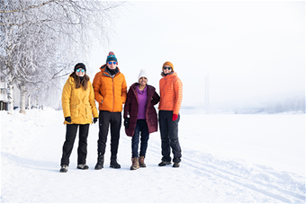 Neljä opiskelijaa seisovat talvimaisemassa.