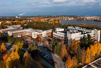 Lapin yliopiston päärakennus ilmasta kuvattuna, taustallaan Rovaniemen kaupungin siluetti. Kuva: Ville Rinne.