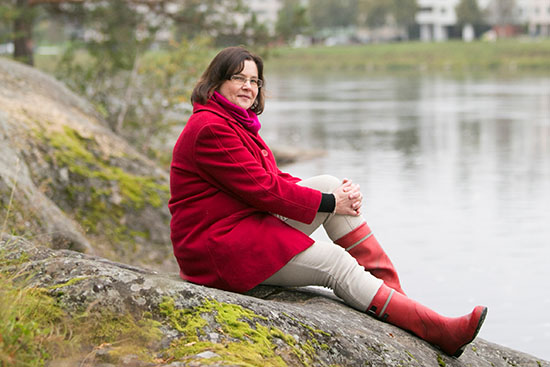 Tuija Turunen istuu rannalla.