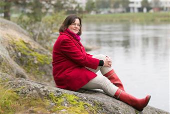 Tuija Turunen istuu rannalla.