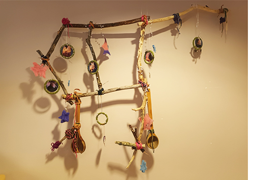 Seinälle kiinnitetty Iso Karhu -installaatio, joka on tehty oksista, erilaisista puisista pienesineistä ja valokuvista ja joka mukailee Iso Karhu -tähtikuvion muotoa.