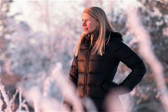 Mira Alhonsuo, taustallaan lumisia puita. Valokuva: Marko Junttila.