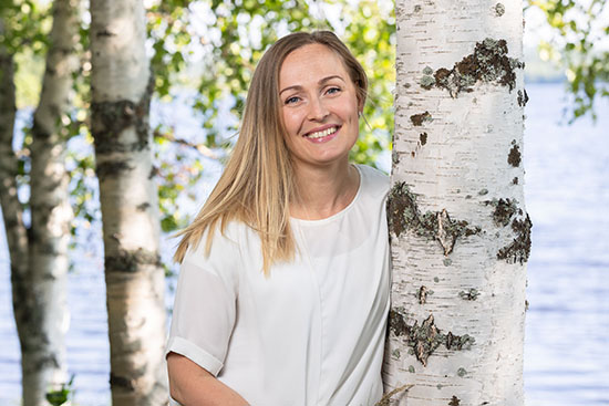 Puolipotretissa Nina Seljo koivujen keskellä. 