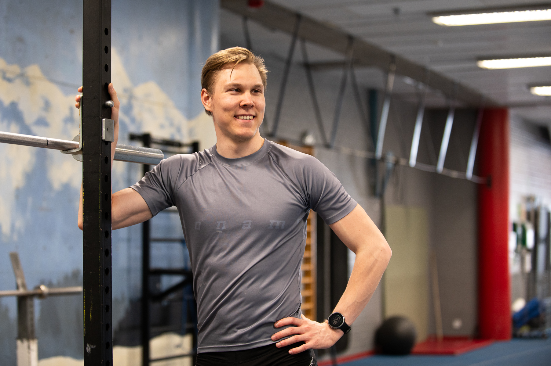 Mies hymyilee urheiluhallissa kameralle.