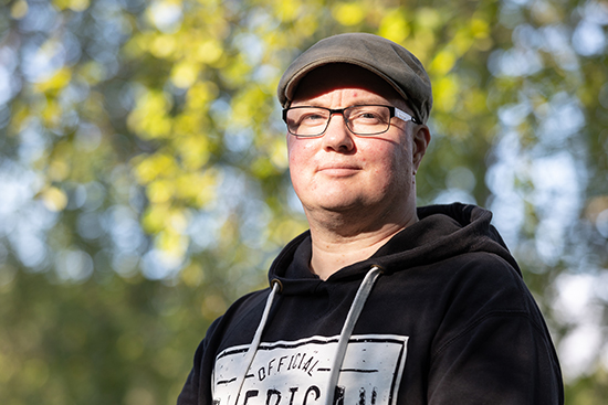 Samuel Salovaara taustallaan kesäisiä lehtipuita.