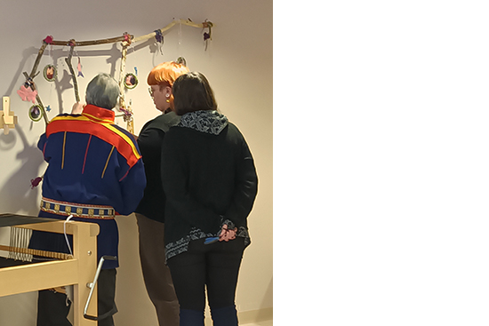 Kolme eri-ikäistä ihmistä selin katsomassa seinälle ripustettua Iso Karhu -installaatiota.