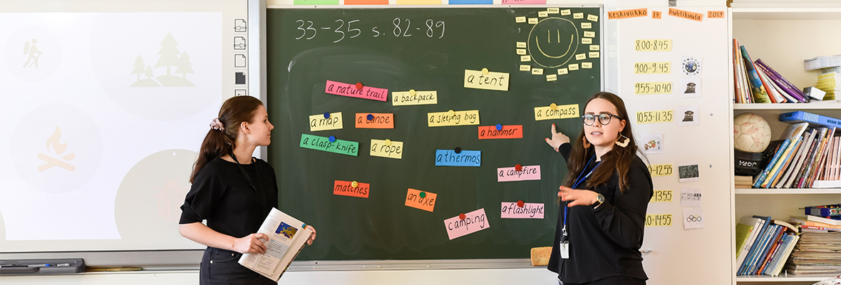 Opetustilannekuva luokassa. Kuvassa kaksi henkilöä liitutaulun edessä.