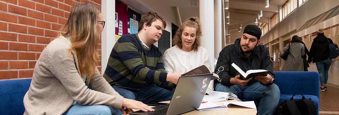 Neljä henkilöä istuvat yhdessä tietokoneen ääressä.