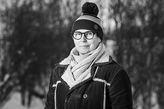 Mustavalkoinen puolipotretti Hanna Peltomaasta, taustalla metsää.