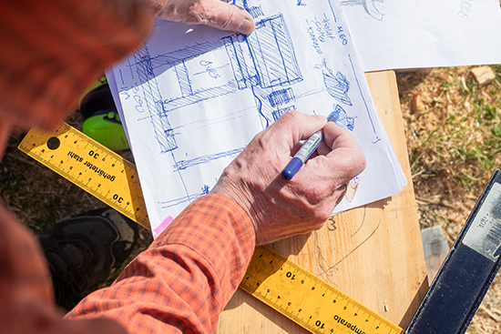 Timo Jokela hahmottelee mustekynällä paperille ympäristötaideteoksen suunnitelmaa. Kuva: Aki Lintumäki.