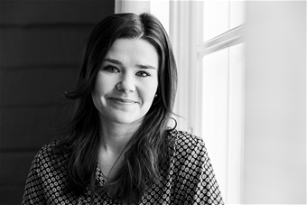 Mustavalkoinen puolipotretti hymyilevästä Susanna Rivisestä. 