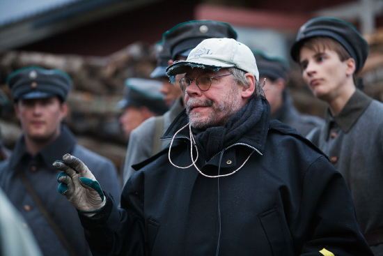 Elokuvaohjaaja Lauri Törhönen ohjaamassa Raja 1918 -elokuvan kuvauksia, taustallaan sotilasasuihin pukeutuneita näyttelijöitä. Kuva: Raimo Paananen.