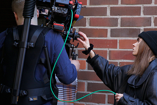 Henkilö kantaa kameraa ja toinen henkilö säätää sitä Aatos-fiktioelokuvan kuvauksissa.