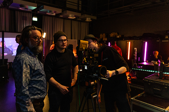 Kolme henkilöä tarkastelee kameraa virtuaalituotantostudiossa Lapin yliopistolla. Kuva: Ville Rinne.