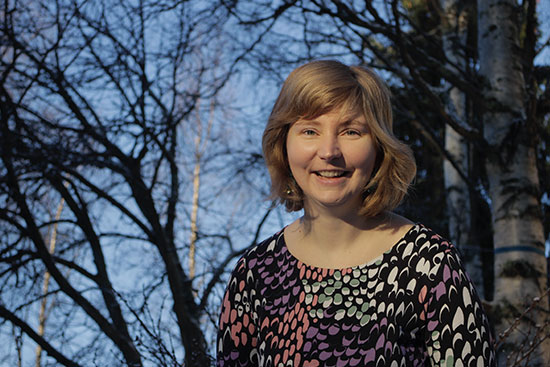 Kuvassa Annamari Manninen, taustalla lehdettömiä puita syysauringossa.