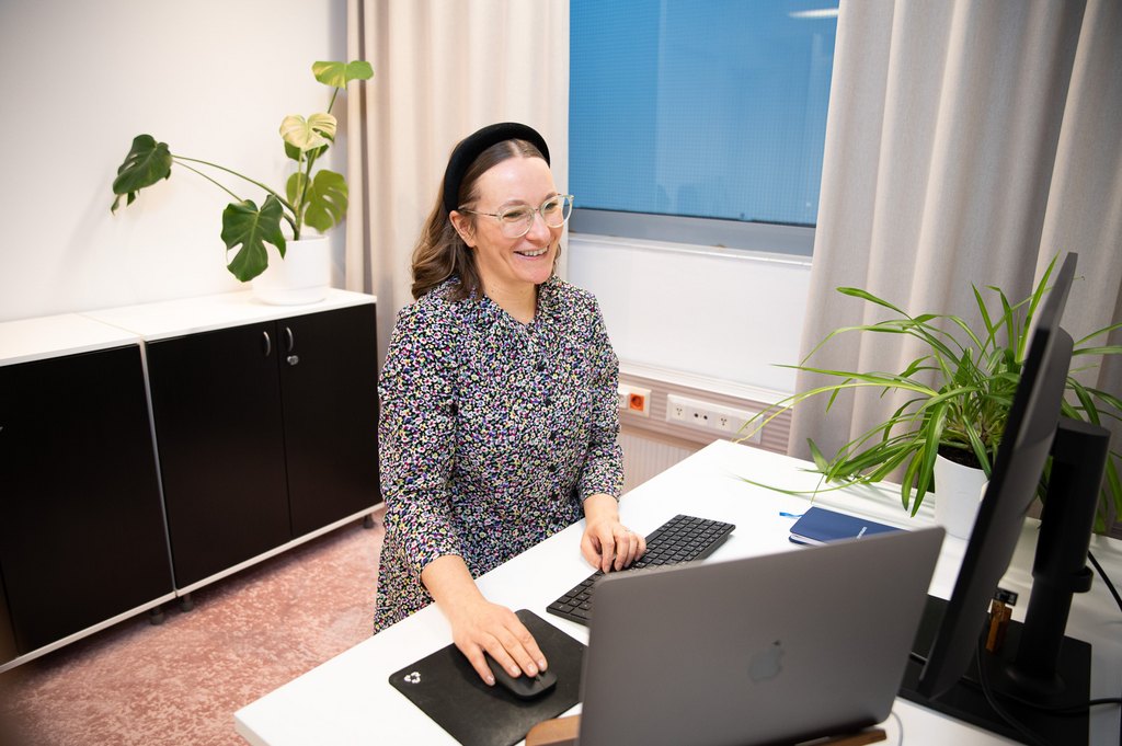 "Nauravainen nainen tietokoneen ääressä."