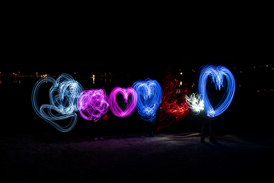 Sydämen muotoisia erivärisiä valoilla tehtyjä kuvioita pimeässä kaupunkiympäristössä.