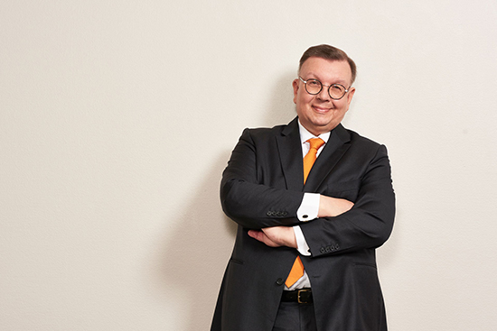 Hymyilevä Petteri Uoti nojaa seinään kädet ristissä rinnalla.