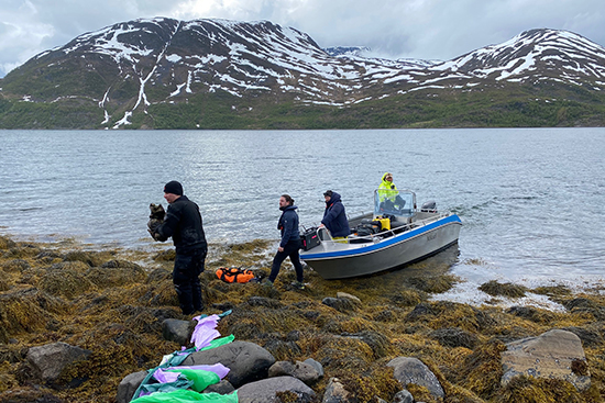 Áfruvvá / Mermaid -elokuvan työryhmää rantautumassa veneellä kuvauskohteeseen Jokelfjordissa, taustallaan vuoria. Kuva: Suvi Autio.