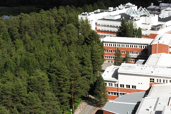 Lapin yliopiston päärakennus ja sen takana olevaa metsää ilmasta kuvattuna.