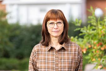 Anniina Koivurova, taustallaan pensaita Lapin yliopiston piha-alueella. Kuva: Ville Rinne.