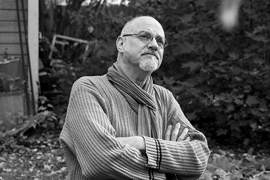 Michael Marnin Jacobs istuu puutarhassa ja katsoo yläviistoon.