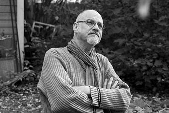 Michael Marnin Jacobs istuu puutarhassa ja katsoo yläviistoon.