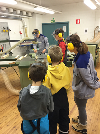 Rantavitikan koulun 1. luokan oppilaita seuraamassa puun käsittelyä konepajassa