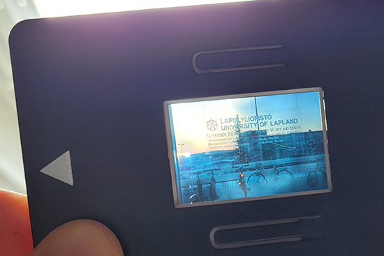 Näkymä Pienteollisuustalon ikkunan läpi aseteltuna diakehykseen, jota käsi pitää valoa vasten.